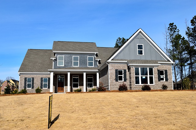 Two-story single family home on a green lawn with columns and a stucco/brick exterior.